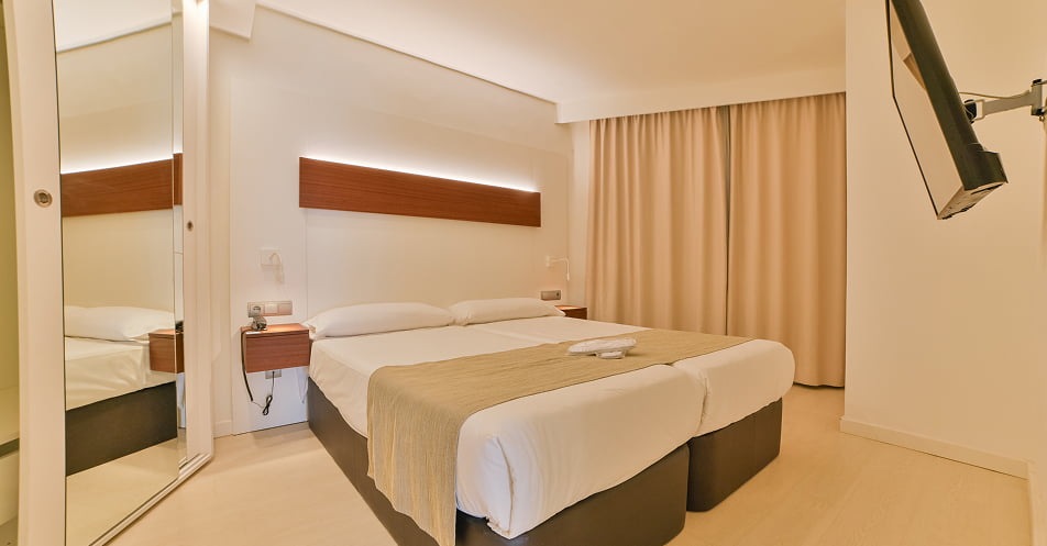 Schlafzimmer mit zwei Einzelbetten nebeneinander und Flachbildfernseher