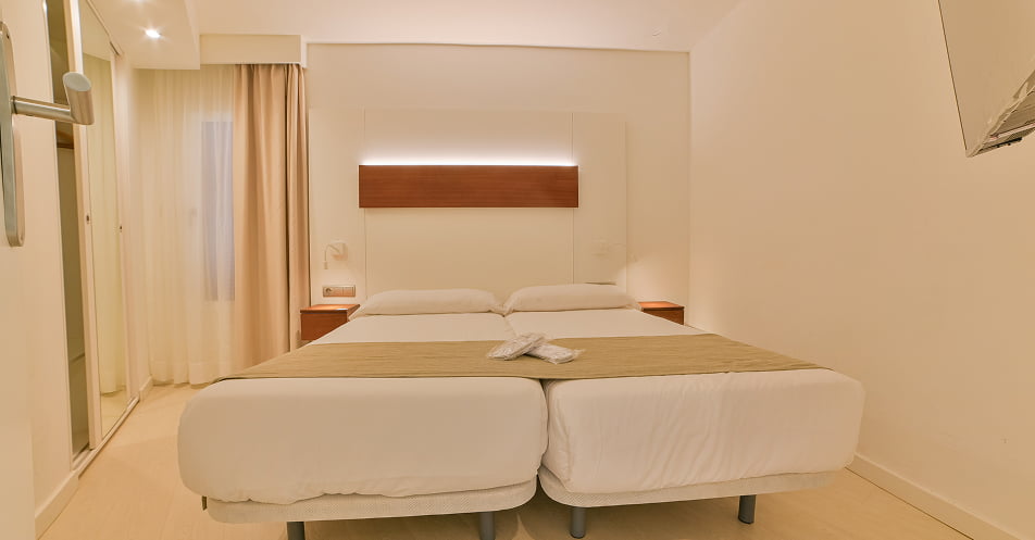 Schlafzimmer mit zwei Einzelbetten in den Farben Weiß und Sand