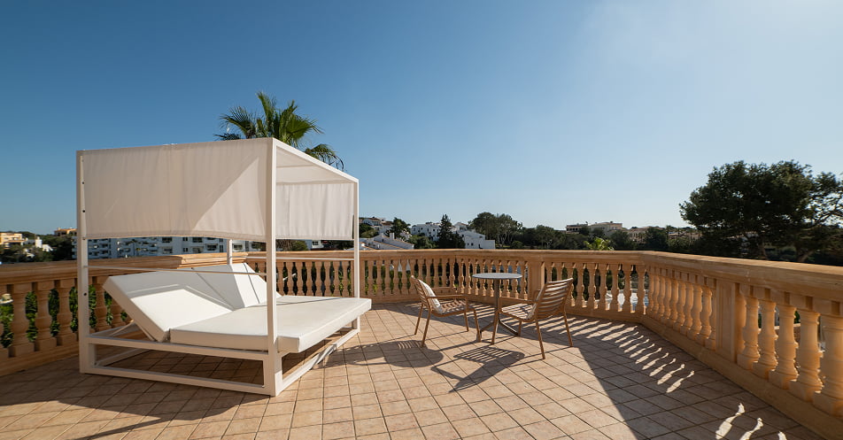 Große Terrasse mit balinesischem Bett, Tisch und Stühlen.